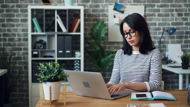a-woman-sitting-at-a-desk-using-a-laptop-computer